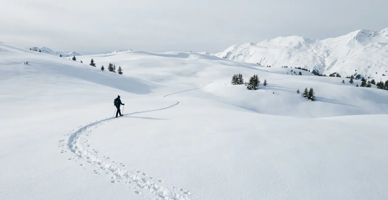 Randonneur en raquettes traversant un paysage enneigé immaculé avec traces dans la neige fraîche