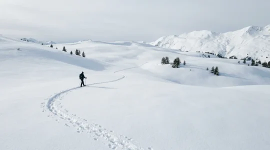 Randonneur en raquettes traversant un paysage enneigé immaculé avec traces dans la neige fraîche