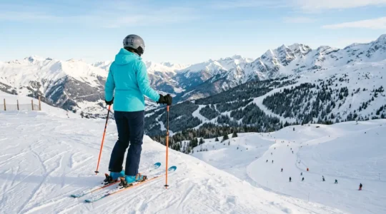 Skieur débutant adulte regardant une pente de ski enneigée avec appréhension et détermination