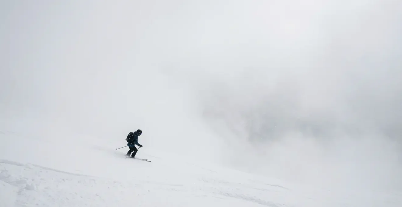 Skieur dans le brouillard épais d'un jour blanc en montagne