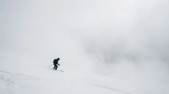 Skieur dans le brouillard épais d'un jour blanc en montagne