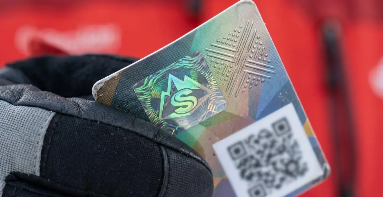 Gros plan sur une main tenant une carte professionnelle de moniteur avec un QR code visible
