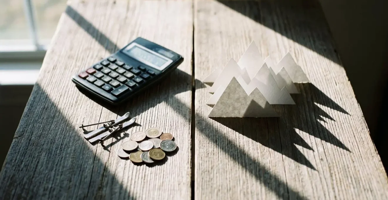 Calculatrice et documents financiers sur table en bois avec équipement de ski flou en arrière-plan