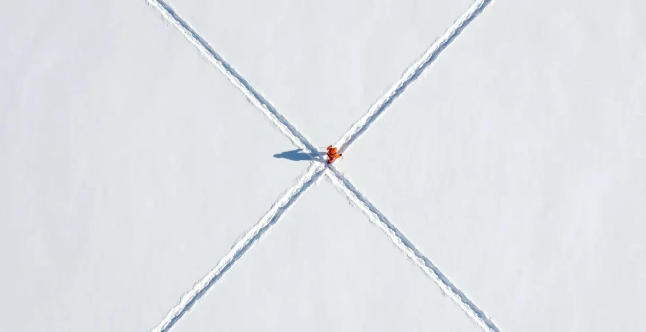 Vue aérienne d'un sauveteur effectuant un pattern de recherche en croix dans la neige
