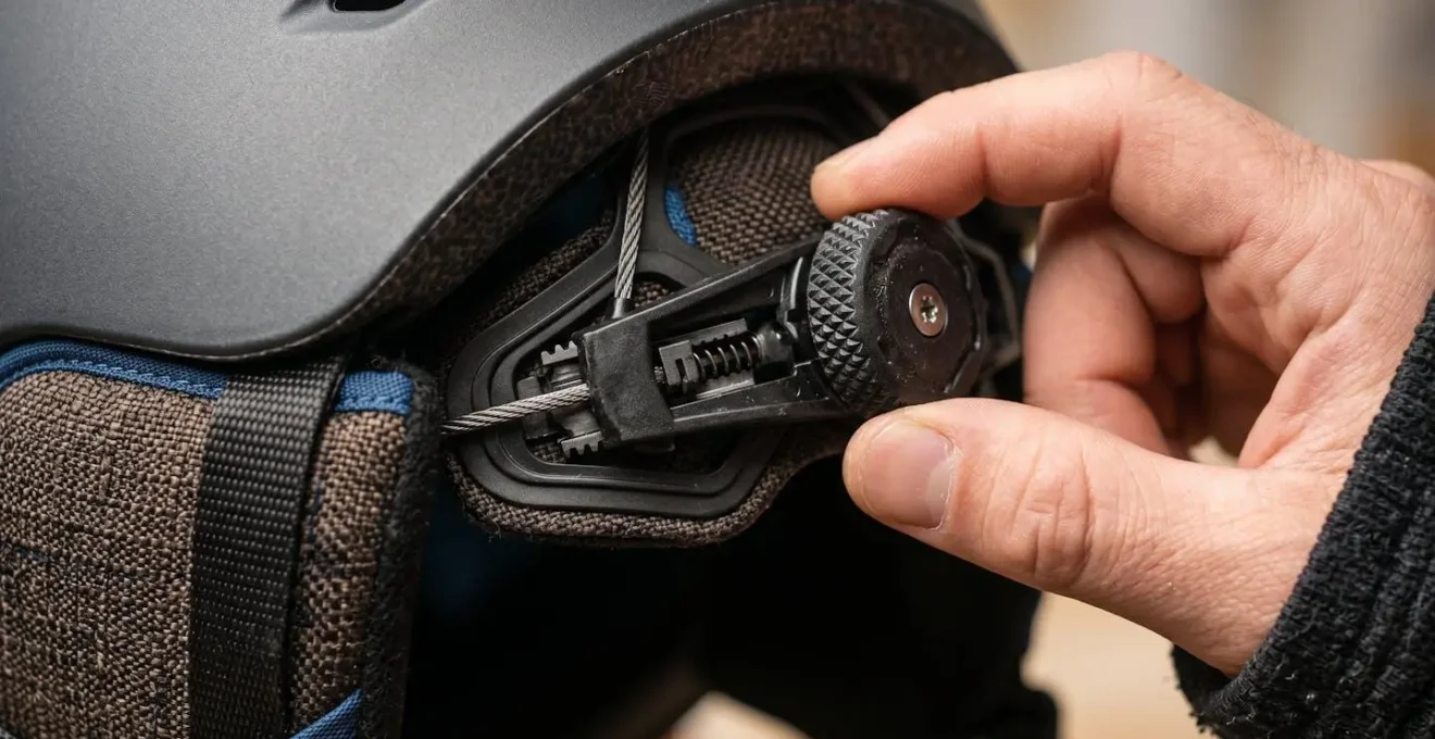 Main ajustant la molette de réglage d'un casque de ski en gros plan